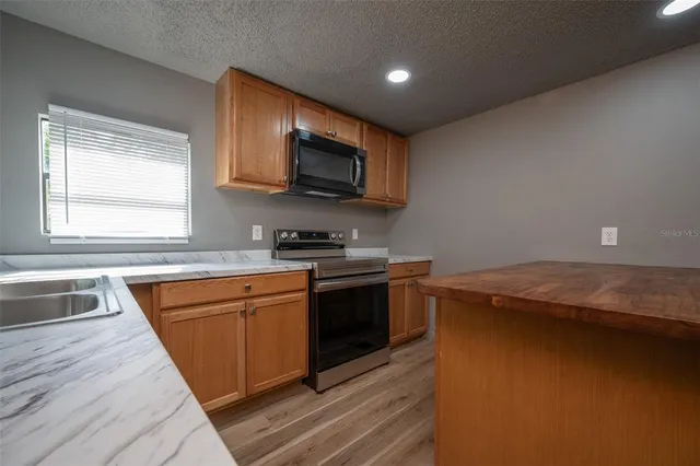 a kitchen with stainless steel appliances granite countertop a sink a stove and a microwave oven