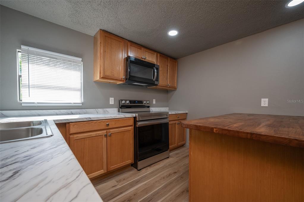 5027 Southwest 69 Street Gainesville, FL 32608 - Photo 7 of 21 a kitchen with stainless steel appliances granite countertop a sink a stove and a microwave oven
