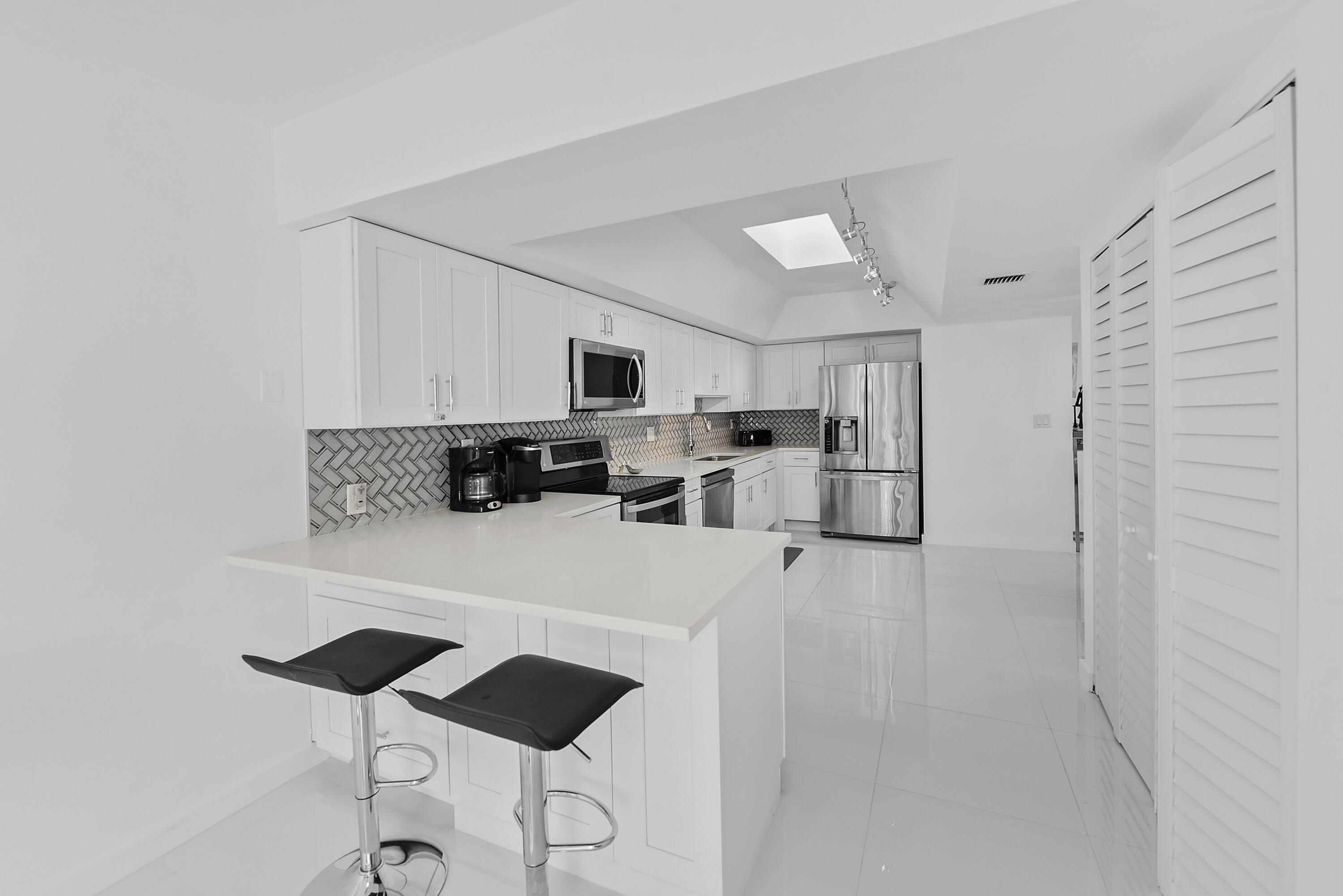 7369 Orangewood Lane, Unit 303 Boca Raton, FL 33433 - Photo 14 of 56 a kitchen with stainless steel appliances a refrigerator stove microwave and white cabinets