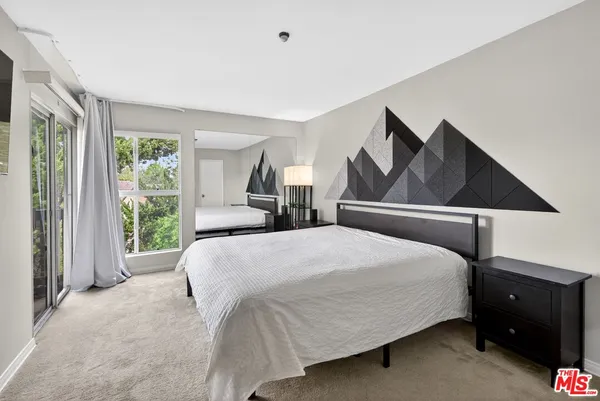 a bedroom with a bed and large windows