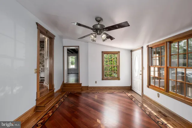 a view of an empty room with wooden floor and stairs