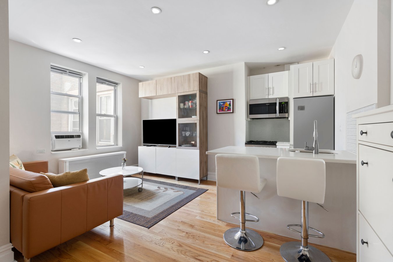 a living room with furniture a flat screen tv and kitchen view
