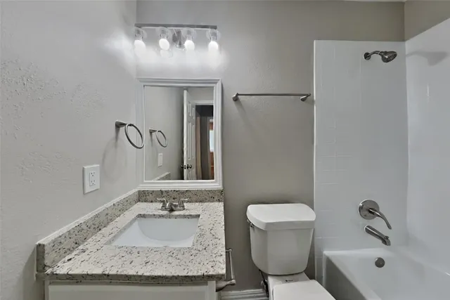 a bathroom with a granite countertop sink a toilet and bathtub