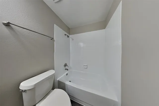 a white toilet and tub sitting next to a bathroom sink