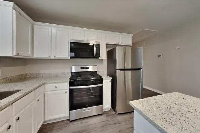 a kitchen with stainless steel appliances granite countertop a refrigerator stove and white cabinets