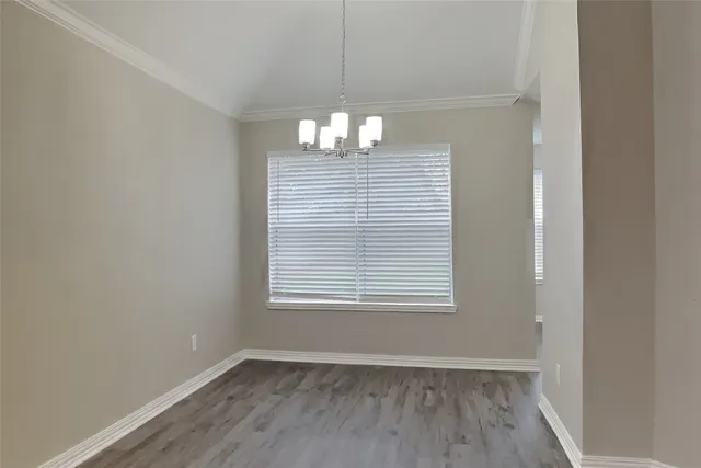 an empty room with wooden floor exposed radiator and windows