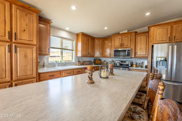 a kitchen with stainless steel appliances a dining table chairs and a refrigerator