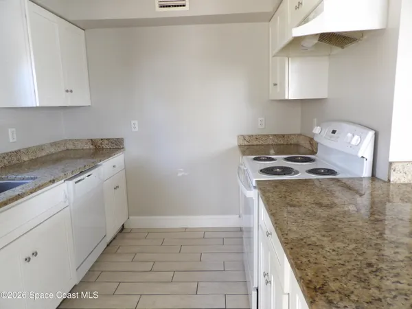 a kitchen with granite countertop a sink stove and cabinets