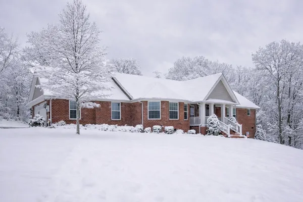 a front view of a house with a yard covered in snow