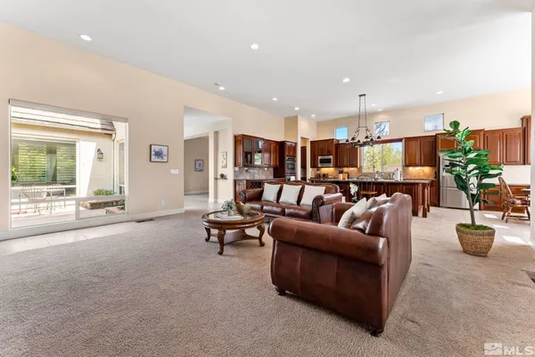 a living room with furniture kitchen view and a large window