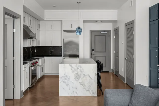 a living room with stainless steel appliances kitchen island granite countertop a refrigerator a stove top oven a sink and dishwasher