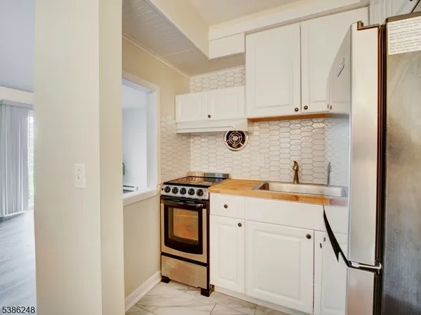 a utility room with stainless steel appliances granite countertop a sink stove and refrigerator