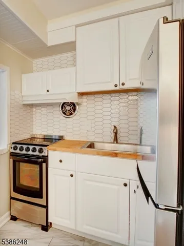 a view of cabinets with stainless steel appliances granite countertop white cabinets and a wooden floor