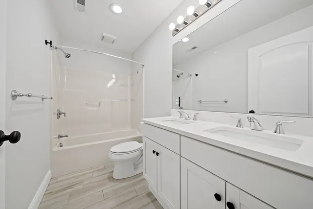 a bathroom with a double vanity sink toilet mirror and shower