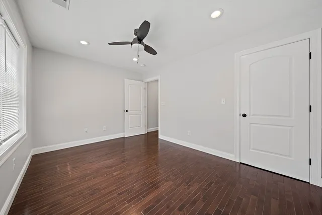 an empty room with wooden floor cabinet and windows