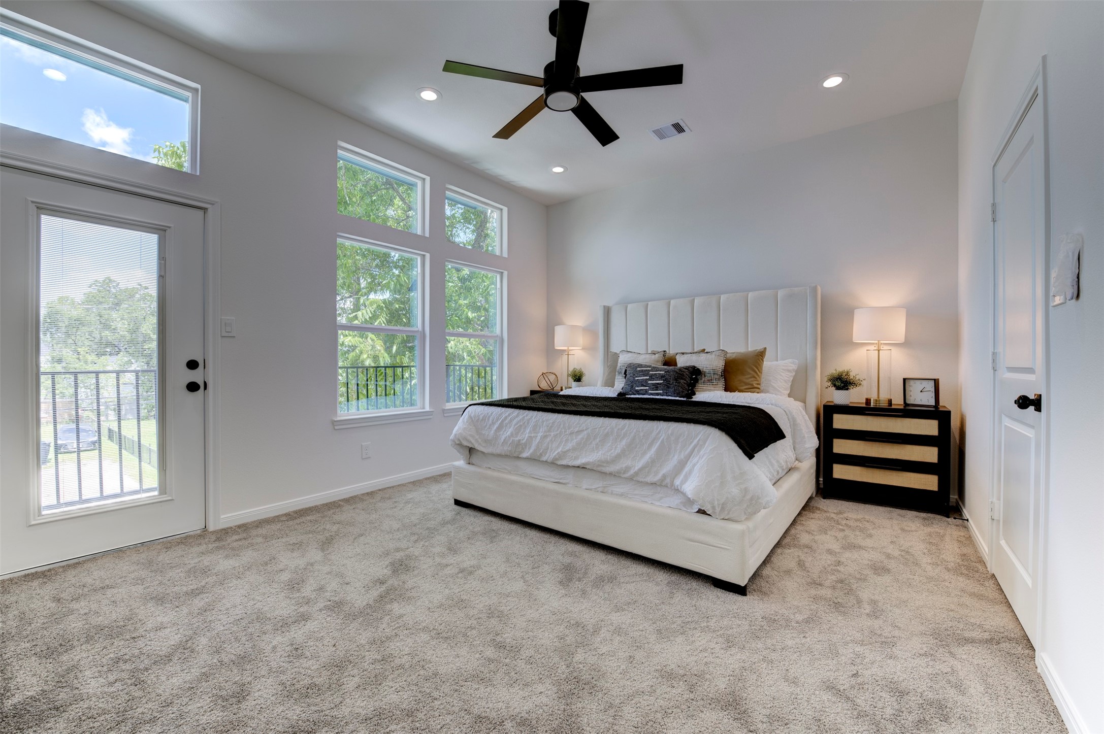 6807 Paris Street Houston, TX 77021 - Photo 25 of 50 Spacious primary bedroom with direct balcony access, dual windows with tree views, recessed lighting, ceiling fan, and plush carpet throughout.