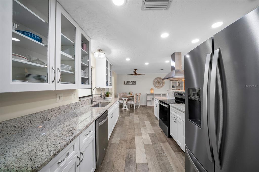 9923 East St Regis Court Inverness, FL 34450 - Photo 49 of 76 a large kitchen with stainless steel appliances granite countertop a refrigerator a sink a stove and a counter space