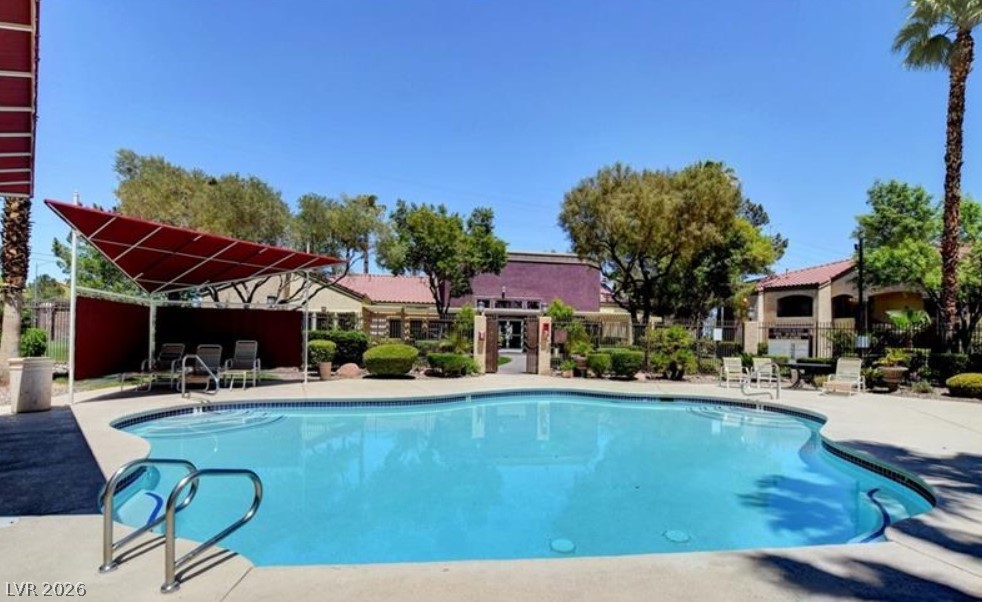 7885 West Flamingo Road, Unit 1008 Las Vegas, NV 89147 - Photo 5 of 29 An inviting pool area, perfect for cooling off, framed by lush landscaping and a bright blue sky.