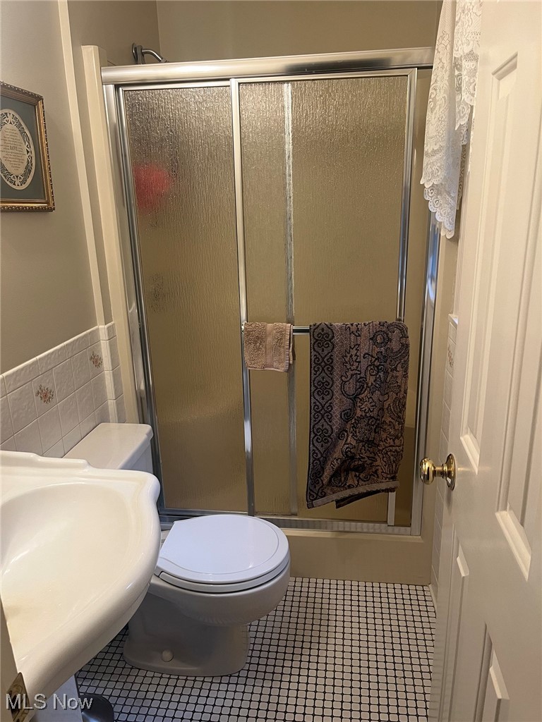 4380 Harner Road Mantua, OH 44255 - Photo 15 of 19 Bathroom with tile walls, a shower stall, tile patterned flooring, and a wainscoted wall