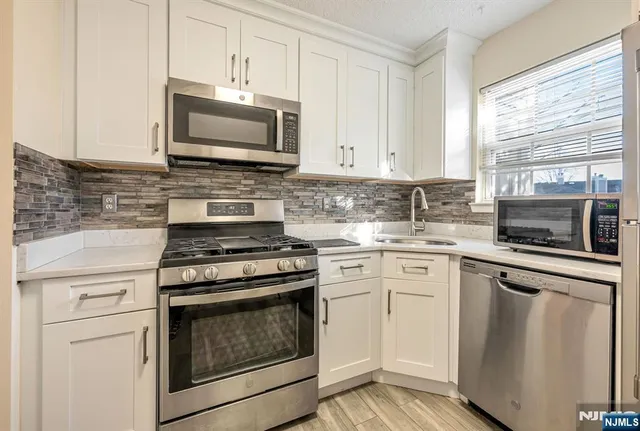 a kitchen with white cabinets and appliances