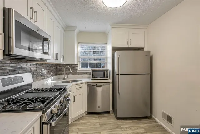 a kitchen with cabinets stainless steel appliances and a window