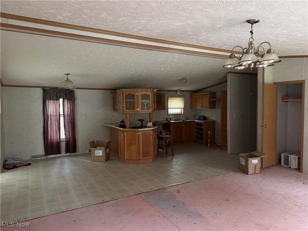 3690 Anderson Anthony Road Leavittsburg, OH 44430 - Photo 6 of 18 Kitchen with decorative light fixtures, brown cabinetry, glass insert cabinets, a chandelier, and light floors