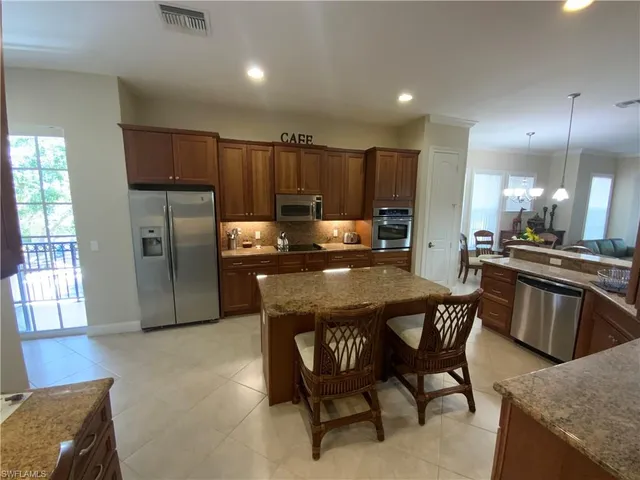 a kitchen with stainless steel appliances granite countertop a stove a refrigerator a sink a dining table and chairs