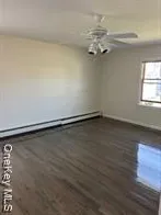 an empty room with a chandelier fan and wooden floor