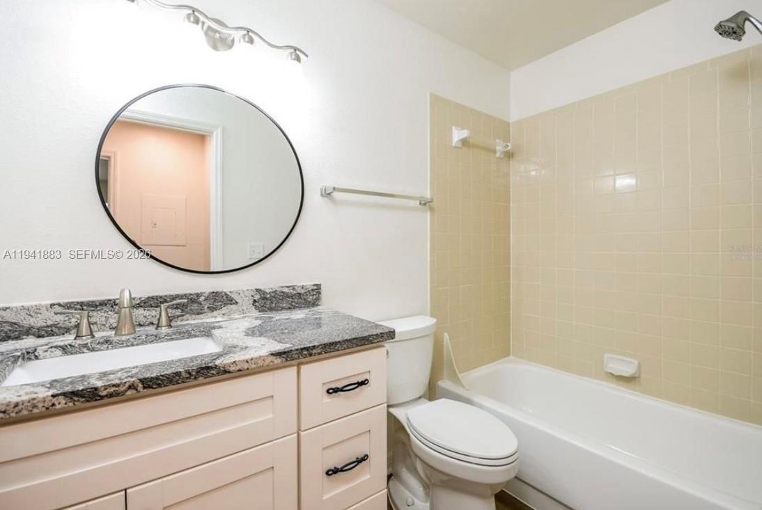 1055 South Hiawassee Road, Unit 2014 Orlando, FL 32835 - Photo 19 of 22 a bathroom with a granite countertop toilet a sink and a mirror