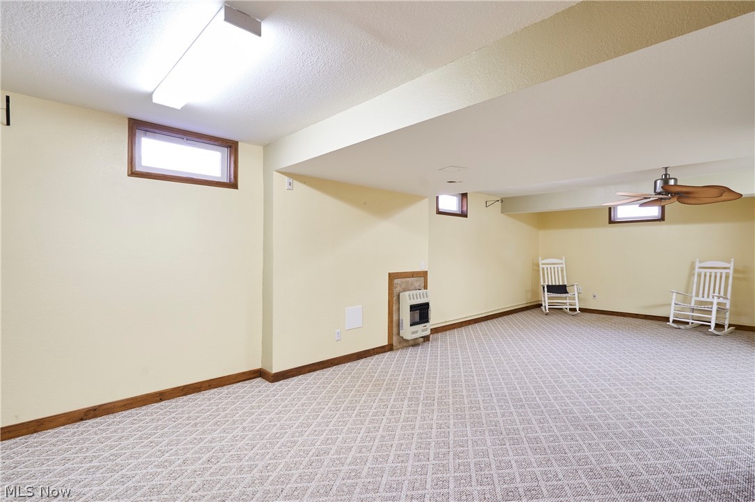 1963 Haines Road Madison, OH 44057 - Photo 22 of 34 Spacious room featuring patterned carpet flooring, wood-framed windows, perimeter wall heater, and a ceiling fan