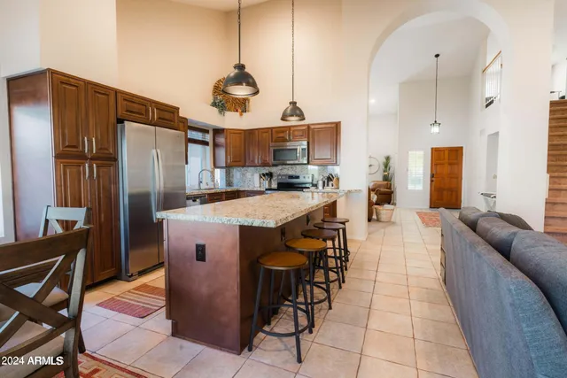 a kitchen with stainless steel appliances granite countertop a refrigerator a stove and a wooden floors