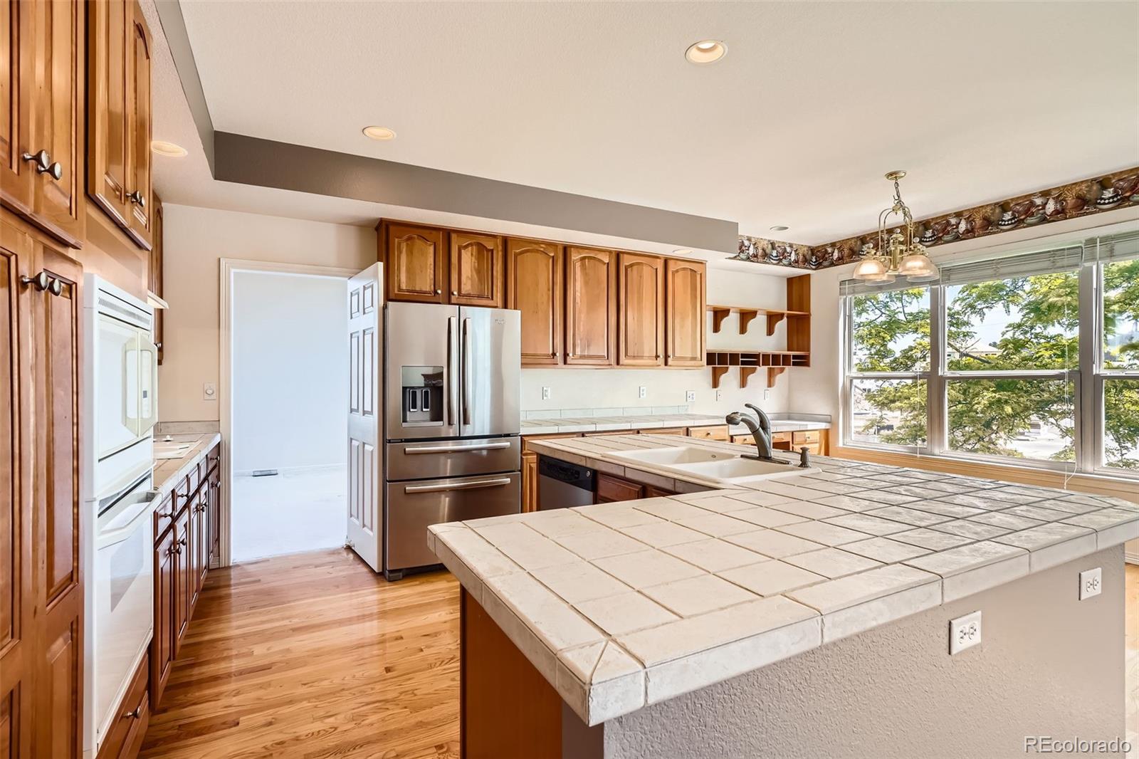 2561 Cactus Bluff Place Highlands Ranch, CO 80129 - Photo 12 of 33 a kitchen with stainless steel appliances a stove top oven a refrigerator a sink and dishwasher with wooden floor