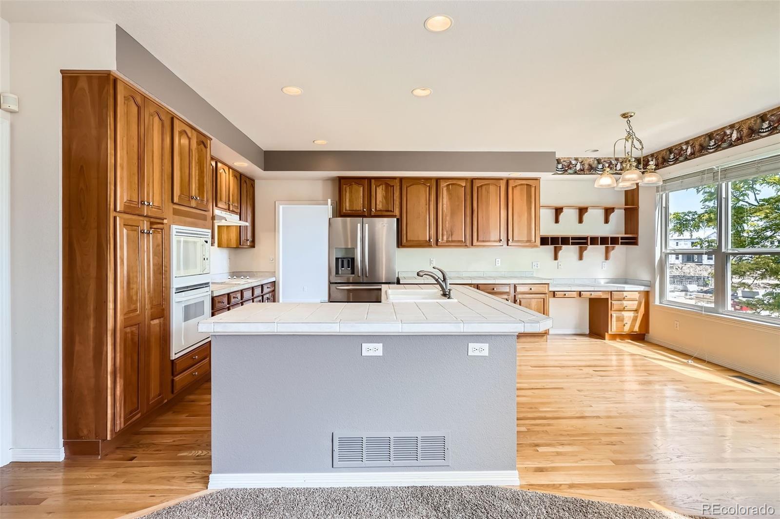2561 Cactus Bluff Place Highlands Ranch, CO 80129 - Photo 10 of 33 a large white kitchen with wooden floors and a fireplace