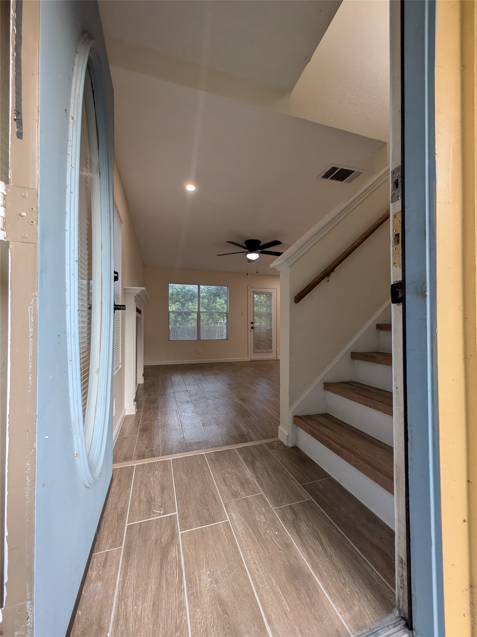 13303 Lyndhurst Street, Unit B Austin, TX 78729 - Photo 2 of 13 A welcoming entryway with wood-look tile flooring leads to a spacious living area and an inviting staircase.