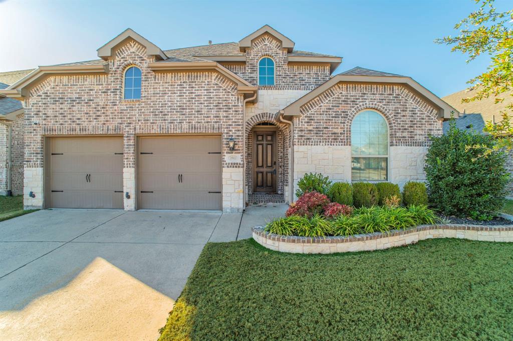French provincial home featuring brick siding, driveway, roof with shingles, and a front lawn
