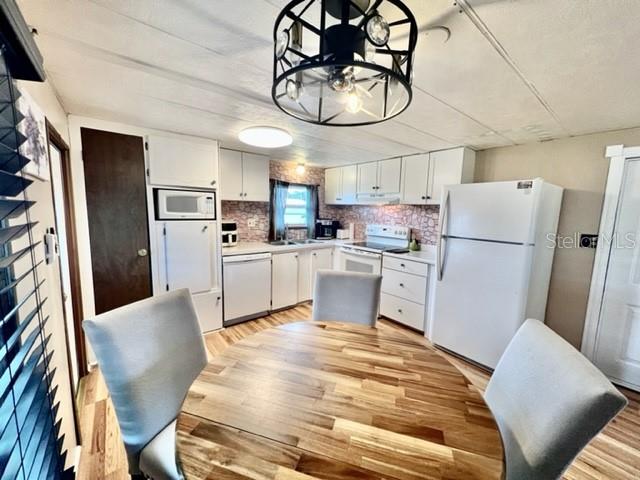 10819 London Drive Port Richey, FL 34668 - Photo 15 of 52 a kitchen with stainless steel appliances granite countertop a refrigerator a sink dishwasher a stove with white cabinets and wooden floor