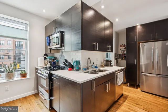 a kitchen that has a sink a stove and chairs
