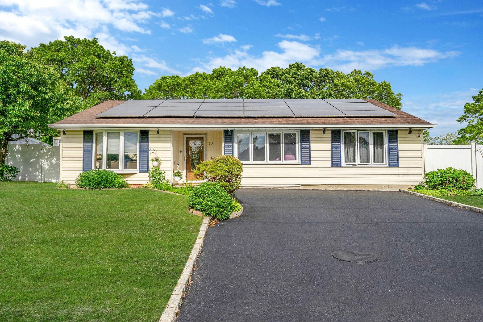 Ranch-style house with asphalt driveway and roof mounted solar panels