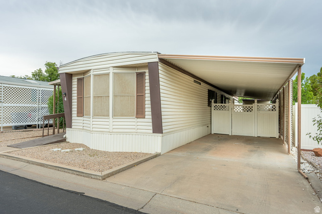 1360 North Dixie Downs Road, Unit 4 St. George, UT 84770 - Photo 3 of 22 Exterior siding with contrasting trim, bay windows with louvered shutters, covered carport, concrete driveway, and a white lattice fence