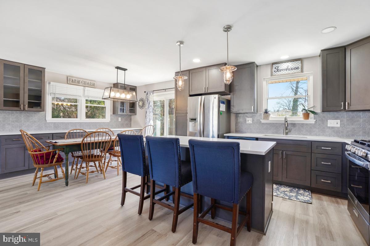 6703 Anders Terrace Springfield, VA 22151 - Photo 12 of 33 a kitchen with stainless steel appliances granite countertop wooden floor dining table and chairs