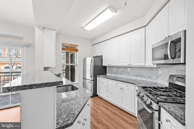 a kitchen with stainless steel appliances a sink stove refrigerator and cabinets