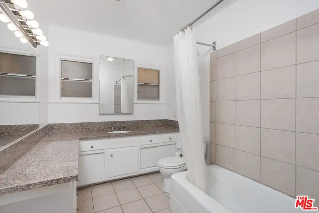 a bathroom with a granite countertop sink a toilet a mirror and bathtub