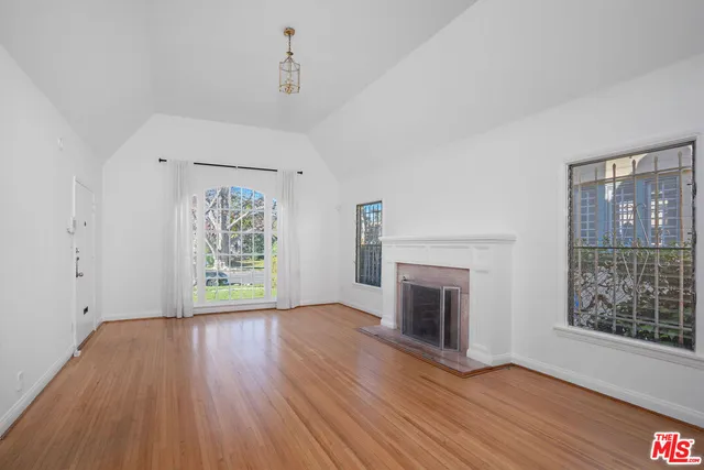an empty room with windows fireplace and wooden floor