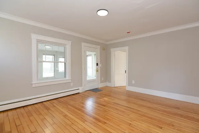 a view of an empty room with wooden floor and a window