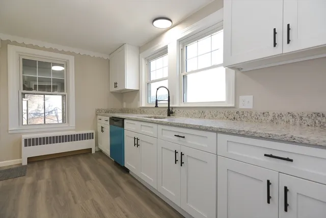 a kitchen with granite countertop white cabinets and a window