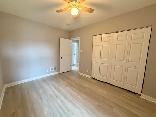 an empty room with wooden floor and fan
