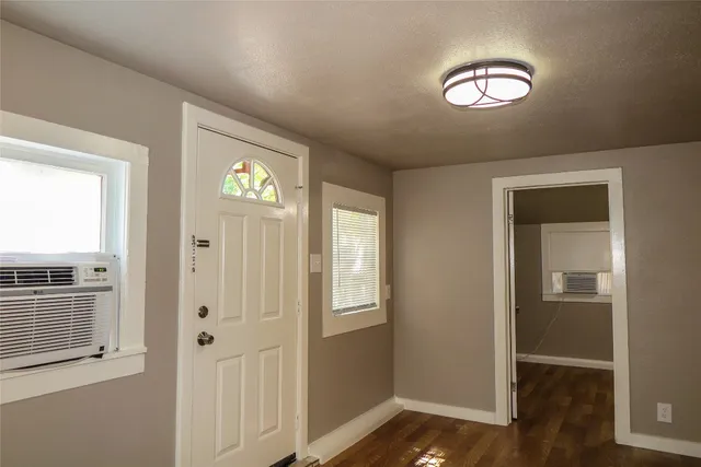 an empty room with wooden floor closet and windows