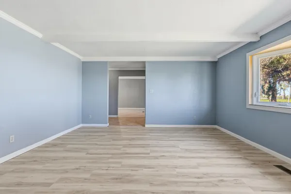 a view of an empty room with window and wooden floor