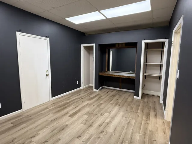 a view of an empty room with a fireplace and wooden floor