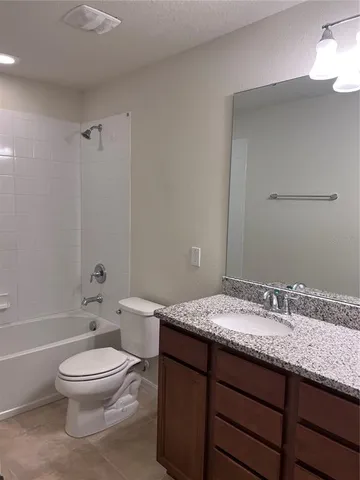 a bathroom with a granite countertop toilet a sink and a mirror